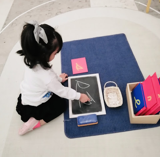 A child practicing writing their “s” on a chalkboard independently
