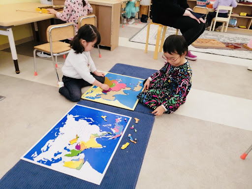 Two children explore the Asia puzzle map which gives them a sensorial experience of geography.