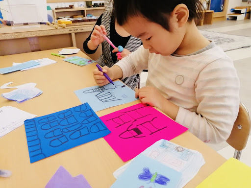 A child makes multiple pages for a booklet about a house.