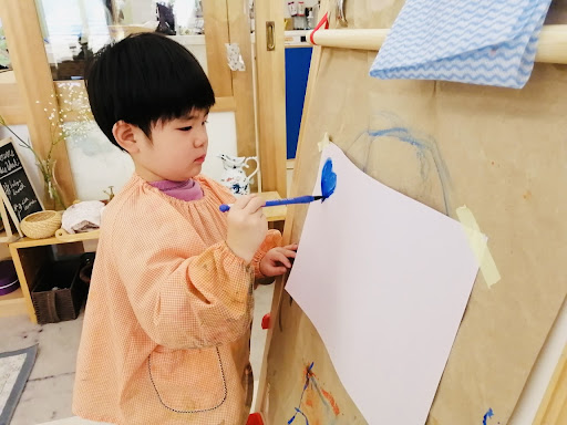 A child paints at the easel.